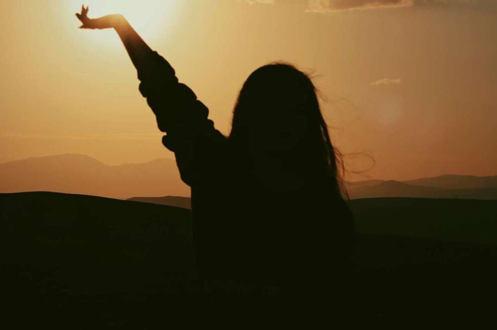 Woman reaching toward the sunrise — psychotherapy for lasting healthy habits at The Design Your Life Centre, Toronto.